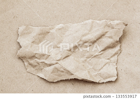 Torn wrinkled piece of craft paper sits on a similar craft surface, creating layered paper texture. Paper layering, edges and folds, copy space Torn wrinkled piece of craft paper sits on a similar craft surface, creating layered paper texture. Paper layering, edges and folds, copy space 133553917