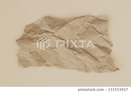Torn sheet of brown textured paper lies on a smooth beige surface, raw edges and uneven paper form. Natural texture of surface, copy space Torn sheet of brown textured paper lies on a smooth beige surface, raw edges and uneven paper form. Natural texture of surface, copy space 133553937