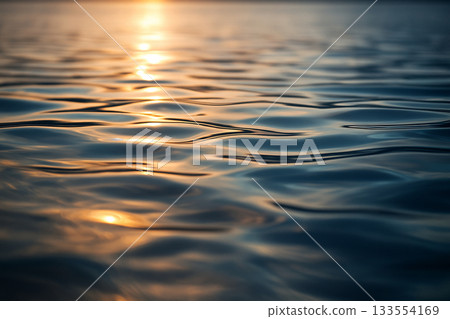 A tranquil scene with the light of the setting sun reflected on the calm water A tranquil scene with the light of the setting sun reflected on the calm water 133554169