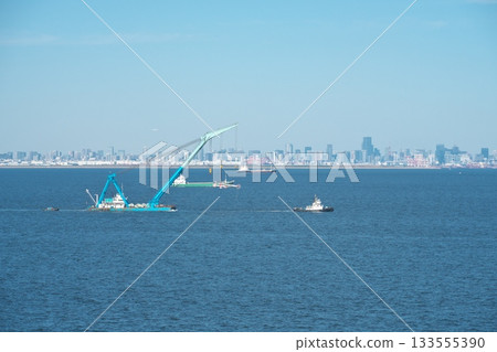 A crane ship being towed by a tugboat through Tokyo Bay A crane ship being towed by a tugboat through Tokyo Bay 133555390