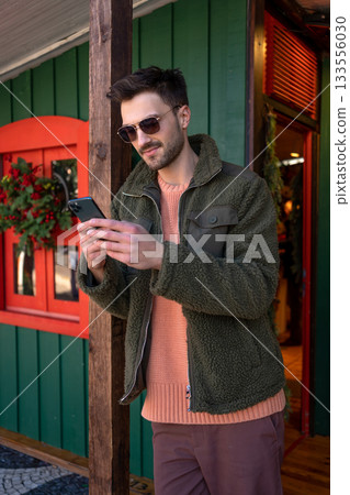 Man in sunglasses using smartphone near green 133556030
