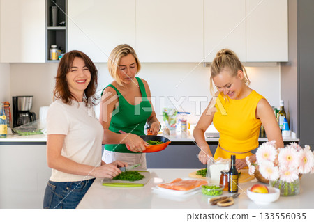 Smiling female friends preparing lunch together in Smiling female friends preparing lunch together in 133556035