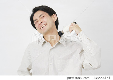 Man in his 20s using a massage gun, white background Man in his 20s using a massage gun, white background 133556131