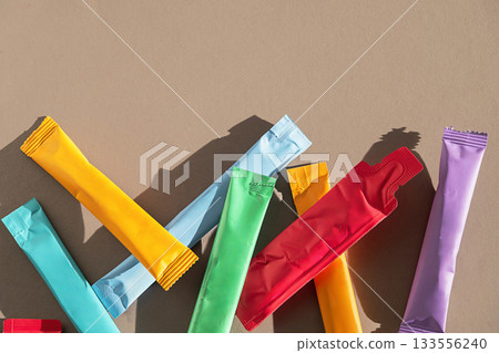 Variety of colorful powder sachets on neutral background with copy space. Variety of colorful powder sachets on neutral background with copy space. 133556240