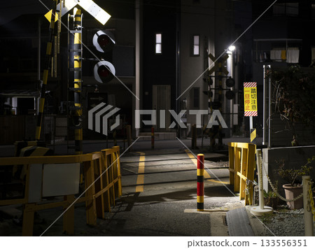 Night view: A small illuminated railroad crossing in a residential area 133556351