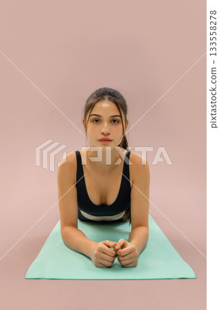 Young woman doing fitness plank on yoga mat in studio, wellness and workout training with yoga mat, healthy lifestyle and fitness routine, sport motivation and home workout concept. 133558278