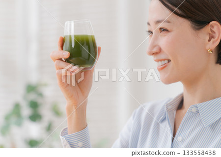 A woman drinking green juice A woman drinking green juice 133558438