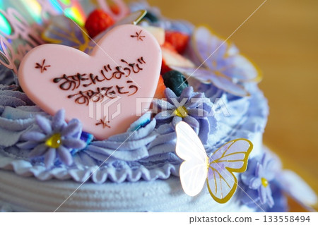 A close-up shot of a gorgeous birthday cake decorated with purple cream and butterfly decorations. 133558494