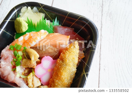 A close-up shot of a seafood bowl filled with a variety of ingredients, including salmon, tuna, shrimp, negitoro (fries), and condiments. A close-up shot of a seafood bowl filled with a variety of ingredients, including salmon, tuna, shrimp, negitoro (fries), and condiments. 133558502