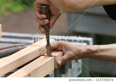 A man cutting wood with a chisel A man cutting wood with a chisel 133559078