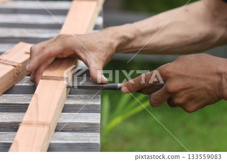 A man cutting wood with a chisel A man cutting wood with a chisel 133559083