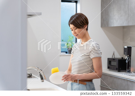 一位婦女在廚房洗碗（家務，家庭主婦） 133559342