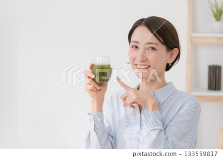 A woman drinking green juice A woman drinking green juice 133559817