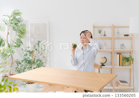 A woman drinking bitter green juice 133560205
