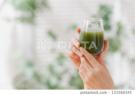 Close-up of a woman drinking green juice Close-up of a woman drinking green juice 133560345
