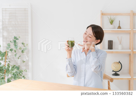 A woman drinking green juice A woman drinking green juice 133560382
