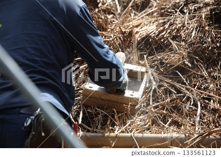 A craftsman repairing a thatched roof A craftsman repairing a thatched roof 133561123