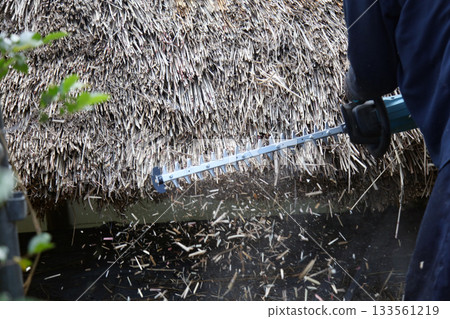 A man trimming a thatched roof A man trimming a thatched roof 133561219
