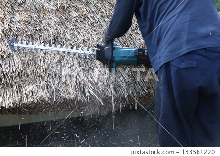 一名男子正在修剪茅草屋頂 133561220