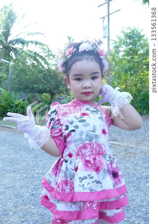Cute Asian girl wearing flower dress and handkerchief in a park Cute Asian girl wearing flower dress and handkerchief in a park 133561368