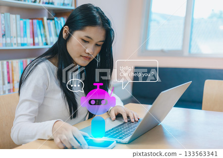 Asian woman using AI chatbot hologram on smartphone and laptop in modern library Asian woman using AI chatbot hologram on smartphone and laptop in modern library 133563341