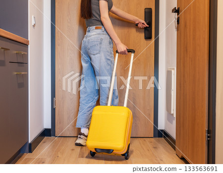 Woman with luggage opening hotel room door Woman with luggage opening hotel room door 133563691