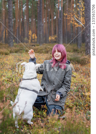 Girl training a dog in autumn forest with pink hair 133563706