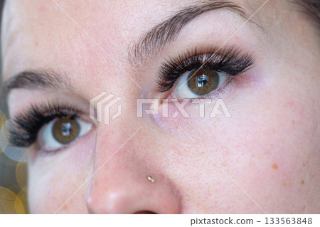 A woman has long extended eyelashes in a close-up with rhinestones. Preparing the image for the holiday 133563848
