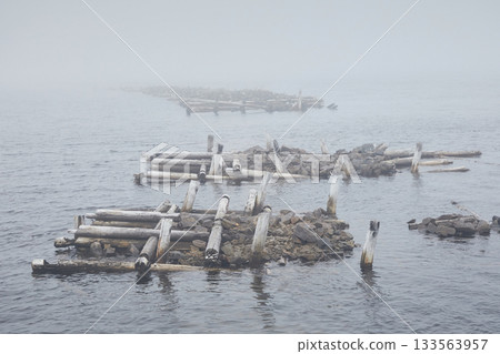 Landscape of a ruined wooden pier on the sea in fog Landscape of a ruined wooden pier on the sea in fog 133563957