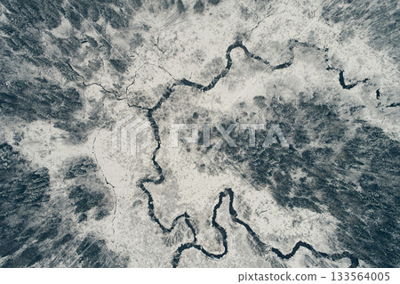Aerial view of the winding river against the backdrop of snowy fields and winter forest. Meander from the top 133564005