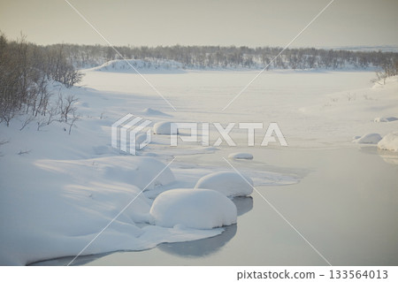 Freezing river with round snowdrifts and steam, close-up. Frosty day, northern winter landscape 133564013