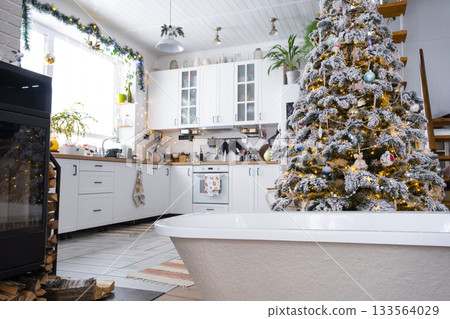 New bathtub under festive Christmas tree as New Year's gift in interior of white modern decorated kitchen. Interior renovation and design, construction and home improvement 133564029