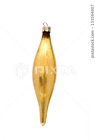 Vintage gold glass Christmas ornament in a long spindle or torpedo shape, with aged patina, isolated on white.  133564807