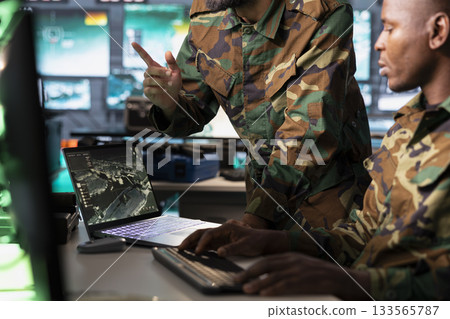 Army officers use reconnaissance tech on laptop to do threat monitoring and target recognition in command post. Military agents employing modern warfare intelligence using software on notebook 133565787