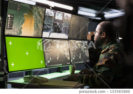 Army telecommunication systems agent using radio and satellite tech, providing combat support, watching mockup screens. Soldier managing communications networks, looking at chroma key monitors Army telecommunication systems agent using radio and satellite tech, providing combat support, watching mockup screens. Soldier managing communications networks, looking at chroma key monitors 133565800