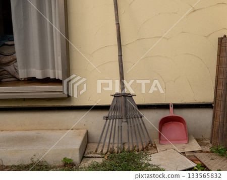 A broom and dustpan leaning against the wall A broom and dustpan leaning against the wall 133565832