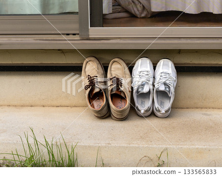 Two pairs of shoes placed side by side under the eaves 133565833