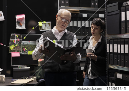 Commissioner and field agent leading an investigation in detective work, reviewing background check files and surveillance photos to gather evidence for criminal justice. Secret mission. Commissioner and field agent leading an investigation in detective work, reviewing background check files and surveillance photos to gather evidence for criminal justice. Secret mission. 133565845