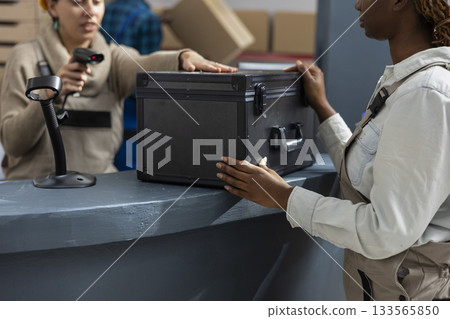 Warehouse activity with diverse employees scanning and registering merchandise, ensuring inventory management and stock control with bar code identification. Import export services. Warehouse activity with diverse employees scanning and registering merchandise, ensuring inventory management and stock control with bar code identification. Import export services. 133565850