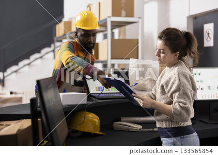 Small business employees scanning cardboard boxes for tags and labels, preparing parcels for express delivery and e-business orders. Retail product distribution in a small scale depot. Small business employees scanning cardboard boxes for tags and labels, preparing parcels for express delivery and e-business orders. Retail product distribution in a small scale depot. 133565854