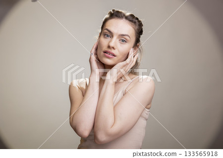 Female model posing with confidence for a cosmetics advertisement, wearing radiant natural makeup in the studio. Graceful positive expression embracing self acceptance and femininity. 133565918
