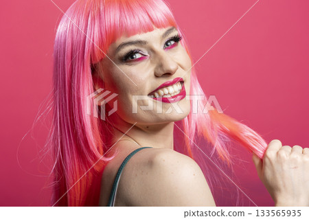 Studio portrait of smiling woman with glowing skin exuding self love, confidence and joy. Gorgeous female model with radiant complexion and joyful expression poses in front of pink background. 133565935