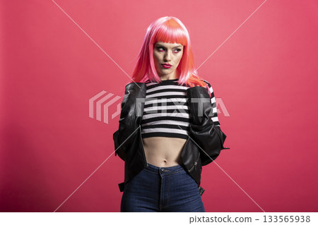 Beautiful lady with expressive makeup and edgy clothing posing over isolated background. Glamorous female enjoys stylish moment in front of camera, blending bold fashion with youthful charm. Beautiful lady with expressive makeup and edgy clothing posing over isolated background. Glamorous female enjoys stylish moment in front of camera, blending bold fashion with youthful charm. 133565938
