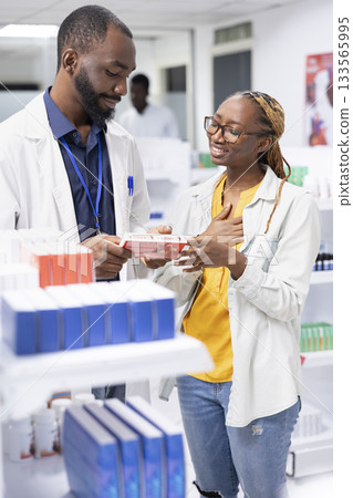 African american pharmacist providing personalized pharmacist service and medication guidance to a pharmacy customer, discussing drugstore medications, vitamins and health products. African american pharmacist providing personalized pharmacist service and medication guidance to a pharmacy customer, discussing drugstore medications, vitamins and health products. 133565995