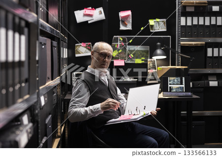 Senior criminologist studies fingerprints and records on a mystery board, using archived case files to uncover new clues in organized crime investigation. Gathering intelligence for a mission. 133566133