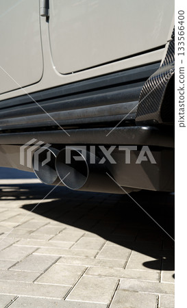 High-performance exhaust system under a sleek vehicle parked in bright sunshine 133566400