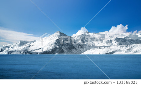 Stunning view of snow-capped mountains with surface of a blue lake and clear blue sky. Natural background 133568023