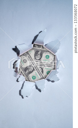 Dollar bills showing from white ripped paper. Concept of business profit, financial growth, investment, and success 133568072