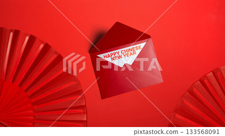 Red envelope and red folding fan with Chinese New Year message on a red background. Happy Lunar or Chinese New Year celebration 133568091