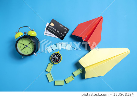 Credit card with alarm clock and antique compass with paper airplane on a blue background. Concept of finance and travel management 133568184